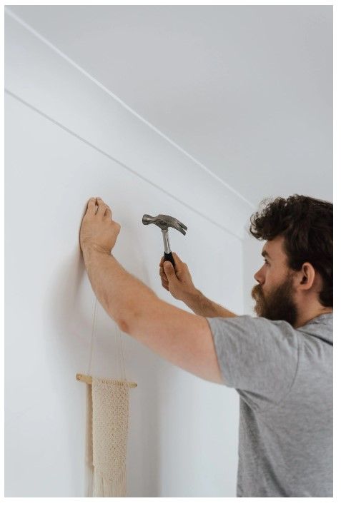 A man holding a hammer and nails the wall.